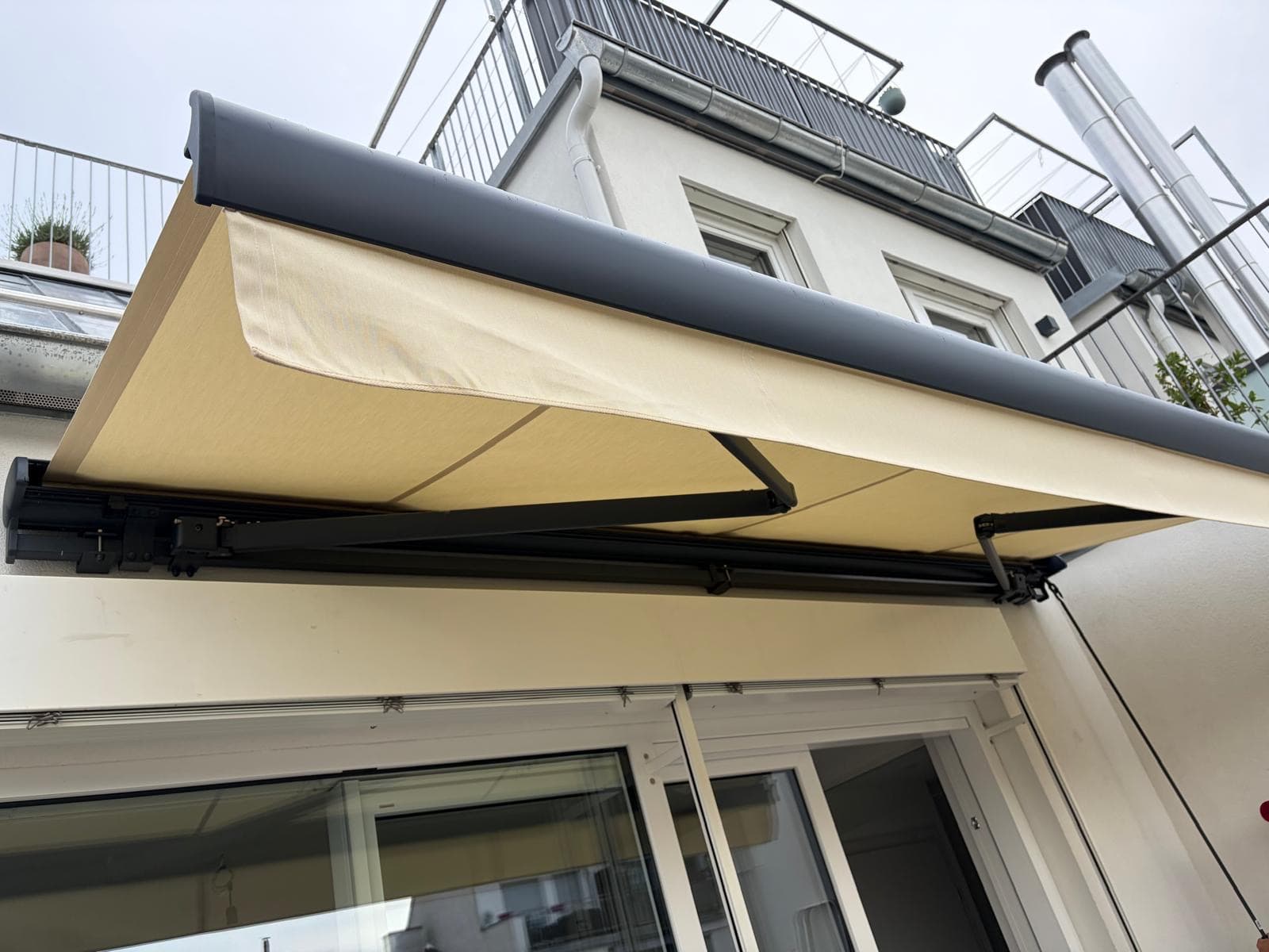 Motorbetriebene Markise mit Gelenkarmen, fachgerecht an der Terrasse montiert